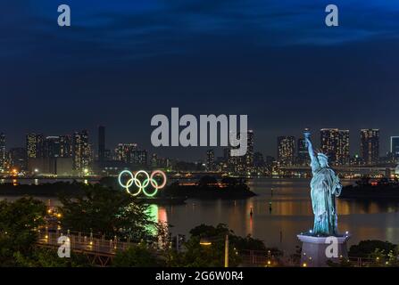 tokyo, japon - juillet 18 2020 : vue nocturne de la réplique de la Statue de la liberté située dans le parc de la plage d'Odaiba, devant l'anneau olympique illuminé Banque D'Images