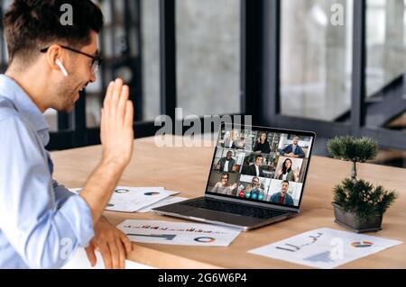 Communication à distance. Homme caucasien ayant une réunion d'affaires virtuelle, parlant avec des personnes multiethniques réussies par appel vidéo, en utilisant un ordinateur portable, siège dans le bureau, la planification de la stratégie de marketing et des idées Banque D'Images