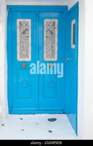 Portes bleues avec rideaux en dentelle blanche sur les fenêtres de Chora sur l'île grecque de Mykonos Banque D'Images