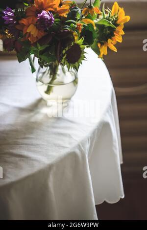 Un bouquet de fleurs sauvages rustiques d'été, des tournesols est sur la table avec une nappe blanche. Style de vie. Copier l'espace. Photo de Moody Banque D'Images