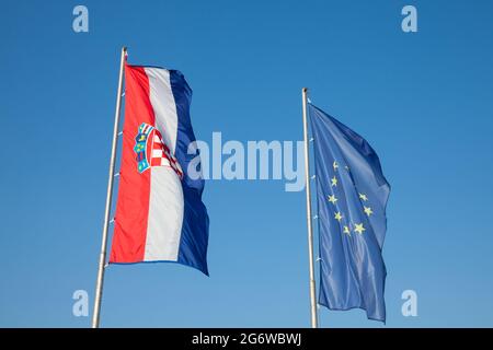 Photo des drapeaux de la Croatie et de l'UE qui se sont enfuis dans l'air derrière un ciel bleu ensoleillé. L'élargissement de l'Union européenne en 2013 a vu la Croatie rejoindre le Banque D'Images