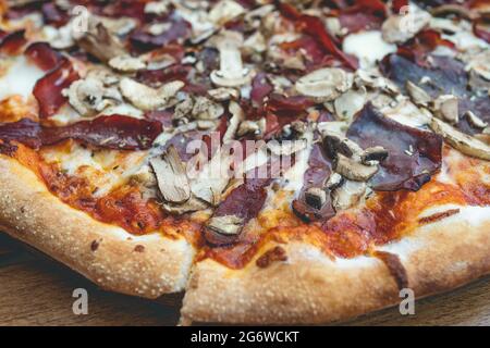 Gros plan sur une pizza cuite en tranches sur la table à la maison ou au restaurant Banque D'Images