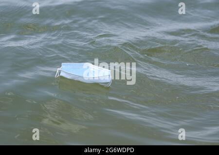 un masque médical flotte sur l'eau. un masque sous forme de bateau. Banque D'Images