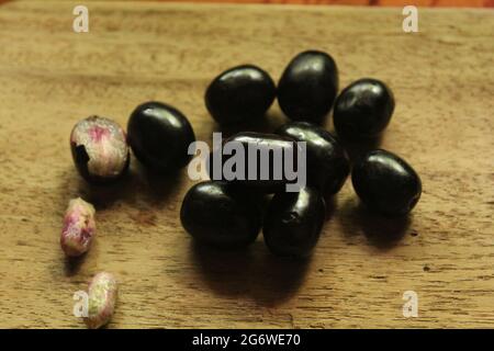 Fruits de prune de Java ou de syzygium sur une surface en bois isolée, vue de dessus, fruit de baies bleues, nouvelle image Banque D'Images