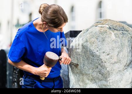 Tailleur femme travaillant sur rocher avec sledgehammer et fer à repasser Banque D'Images