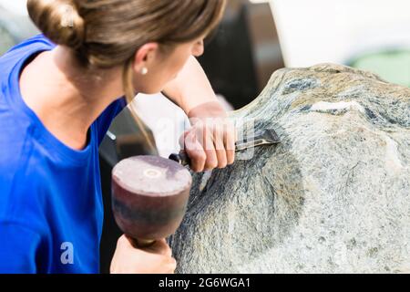 Tailleur femme travaillant sur rocher avec sledgehammer et fer à repasser Banque D'Images