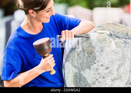 Tailleur femme travaillant sur rocher avec sledgehammer et fer à repasser Banque D'Images