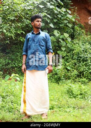 modèle masculin dans des vêtements indiens traditionnels debout dans le jardin lors d'un festival ensoleillé d'onam Banque D'Images