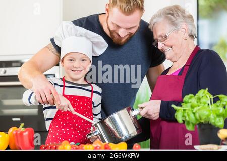 Maman, papa, mamie et son petit-fils ensemble dans la cuisine la préparation des aliments Banque D'Images