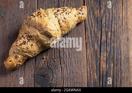 Croissant aux graines de sésame et de lin sur fond de bois ancien. Espace pour le texte Banque D'Images
