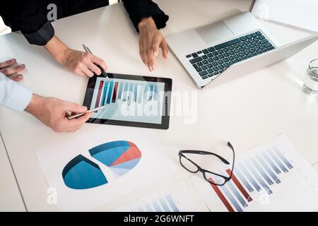 Trois membres d'une équipe de professionnels de l'analyse graphique à barres affichées sur l'ascendant tablet PC Banque D'Images