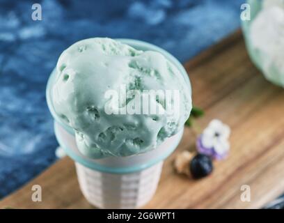 Crème glacée au pistache dans un cornet de gaufres et un vase sur fond bleu Banque D'Images