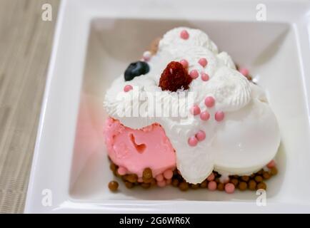 Vue panoramique sur la glace vanille et fraise avec crème fouettée et baies servies sur un dessert blanc, lumière naturelle. Banque D'Images