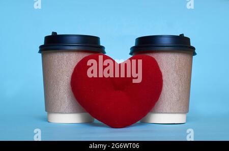 Deux tasses en papier pour le café et un coeur jouet.Espace pour le texte Banque D'Images