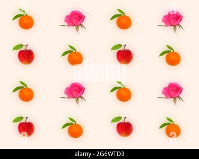 Motif décoratif avec mandarines orange, roses roses et pomme rouge sur fond pêche clair Banque D'Images