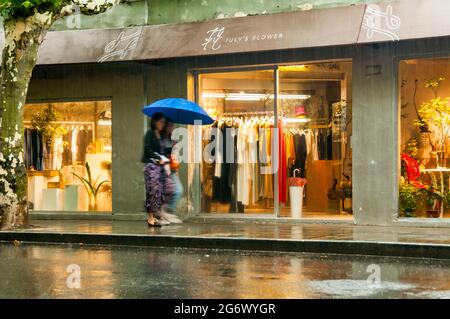 Deux dames marchent devant un fleuriste sur la route Yanqing sous une pluie torrentielles dans l'ancienne concession française de Shanghai, en Chine. Banque D'Images