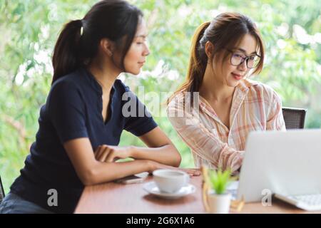 Vue latérale de deux femmes d'affaires consultant sur leur projet sur ordinateur portable dans la salle de réunion Banque D'Images