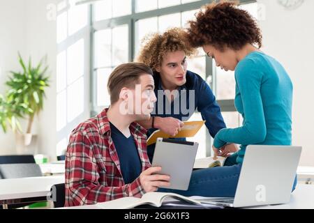 Trois étudiants qui partagent des idées et opinions sur différents sujets et de nouveaux renseignements tirés de cours à l'université Banque D'Images