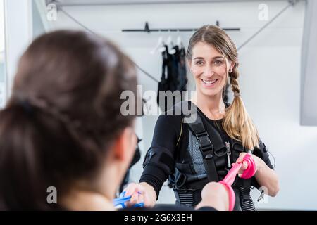 Femme moulante et bosse ayant un entraînement ems ensemble dans une salle de gym Banque D'Images