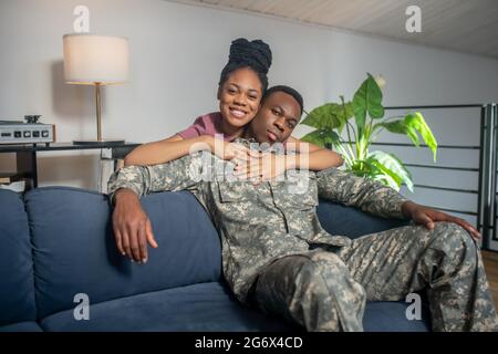 Une jeune femme embrasse les épaules d'un mari militaire Banque D'Images