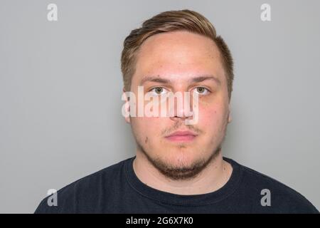 Jeune homme blond sérieux avec barbe de gardien de but dans ses années vingt regardant attentivement la caméra dans un portrait frontal tête et épaules sur blanc Banque D'Images