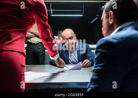 Défendeur d'âge moyen ou le témoin conseillé par l'avocat de signer une déclaration officielle devant le procureur, au cours d'une enquête criminelle dans Banque D'Images