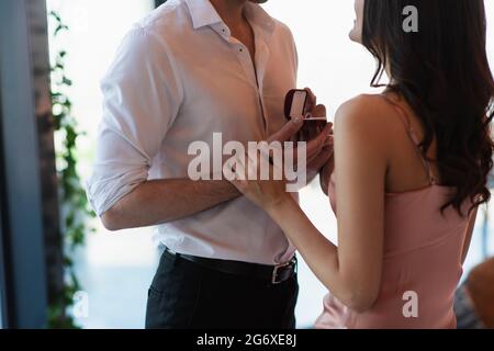 vue rognée de l'homme faisant la proposition à l'amie heureuse en robe sans robe Banque D'Images