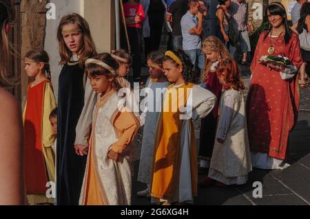 Les jeunes de la région portant un costume médiéval coloré, y compris des jeunes filles pré-adolescentes et un garçon tout-petit, se tiennent main dans la main tandis qu'ils attendent sur la Piazza Guglielmo Marconi à Anagni, Lazio, Italie, pour un signal de marcher dans un pageant historique d'août en l'honneur de Saint Magnus d'Anagni, leur Saint patron. Le spectacle rappelle également le passé d'Anagni en tant que ville des Papes, la résidence d'été du pontife à la recherche d'un refuge plus frais face à la chaleur estivale de Rome. Les filles portent de longues robes de chambre ou manteaux de dessus avec leurs cheveux retenus par des bandeaux décoratifs. Banque D'Images