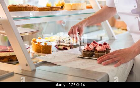 Vente Baker woman putting diverses tartes et gâteaux sur l'affichage Banque D'Images