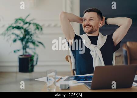 Homme d'affaires heureux se reposant après le travail fait dans son lieu de travail confortable dans un bureau moderne Banque D'Images