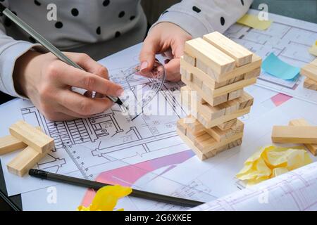 Architecte designer intérieur créatif travail main jouant un jeu de bois de bloc sur le bureau plan architectural de la maison, une palette de couleurs. Femme architecte Banque D'Images