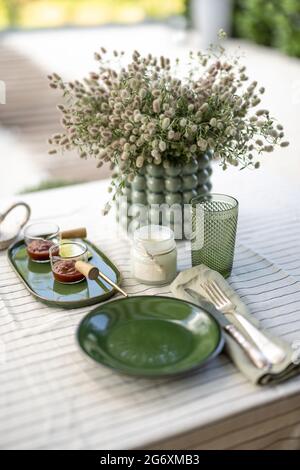 La table du jardin est couverte d'une nappe et décorée de fleurs et de bougies avec de la nourriture pour deux personnes. Dîner d'été à l'extérieur. Banque D'Images