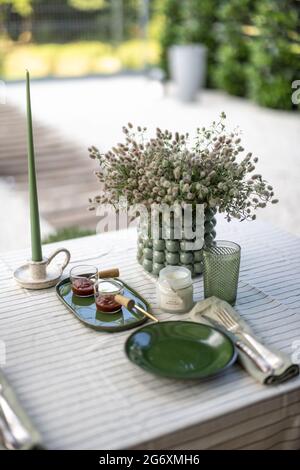 La table du jardin est couverte d'une nappe et décorée de fleurs et de bougies avec de la nourriture pour deux personnes. Dîner d'été à l'extérieur. Banque D'Images