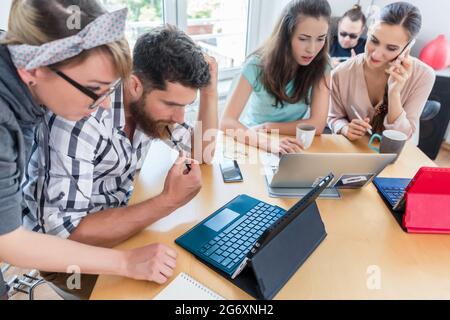 Vue latérale d'un jeune travailleur indépendant dédié analysant une tâche difficile tout en travaillant dans un hub moderne pour les nomades numériques ou un entrepreneur indépendant Banque D'Images