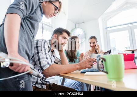 Vue latérale d'un jeune travailleur indépendant dédié analysant une tâche difficile tout en travaillant dans un hub moderne pour les nomades numériques ou un entrepreneur indépendant Banque D'Images