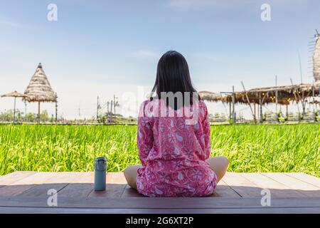 Femme assise sur un sol en bois avec thermos bouteille regarder un magnifique paysage. Banque D'Images