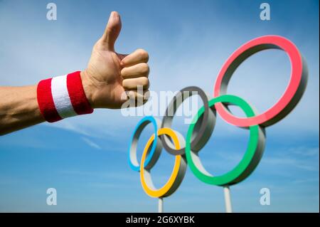 RIO DE JANEIRO - 4 MAI 2016 : la main de l'athlète japonais portant un bracelet rouge et blanc donne un geste de pouce devant les anneaux olympiques debout un Banque D'Images