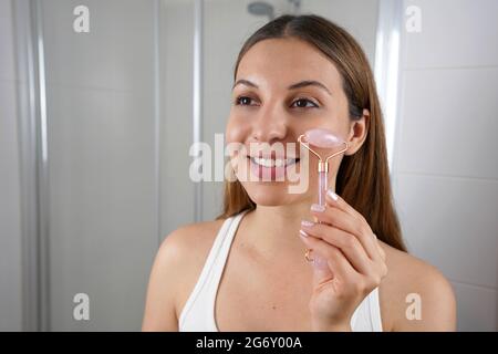 Gros plan d'une jeune femme utilisant un rouleau de cadran en quartz rose naturel Banque D'Images