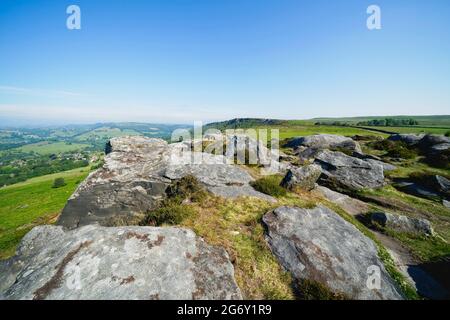 Toutes les formes et tailles d'affleurements de gritstone dépassent du sol le long du sommet de Baslow Edge dans le Derbyshire par un matin d'été brumeux. Banque D'Images