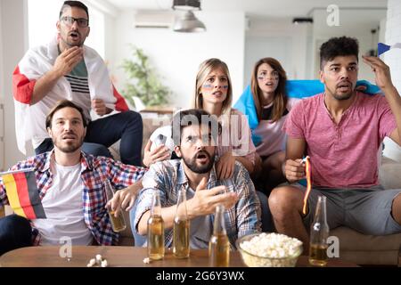 Des amis frustrés et choqués qui regardent un match de football à la maison Banque D'Images