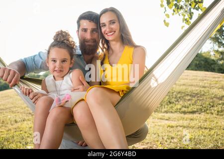 Heureux belle femme et son beau mari posant avec leur fille mignonne pour un portrait de famille pendant les vacances d'été à l'countrysi Banque D'Images