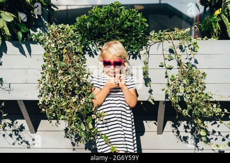 Fille triste en robe rayée et lunettes de soleil dehors Banque D'Images