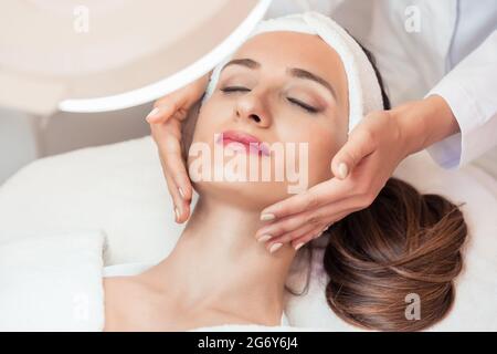 D'un grand angle de vue le visage d'une femme détendue smiling sous l'avantages de massage facial anti-âge dans un centre de beauté contemporaine Banque D'Images