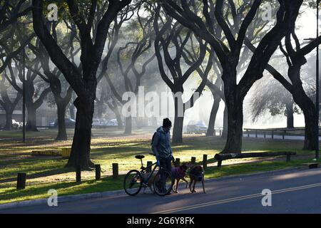 Buenos Aires, Argentine - 5 juillet 2021: Un chien sitter avec son vélo dans un parc brumeux de boques del palermo dans le quartier de Palerme Banque D'Images