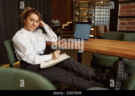 Femme indépendante travaillant sur ordinateur portable au café Banque D'Images