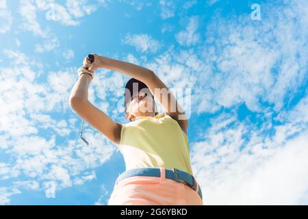 Low angle view of a professional joueur tenant le fer en club avec la concentration pour frapper tout en jouant le golf à l'extérieur contre ciel nuageux Banque D'Images