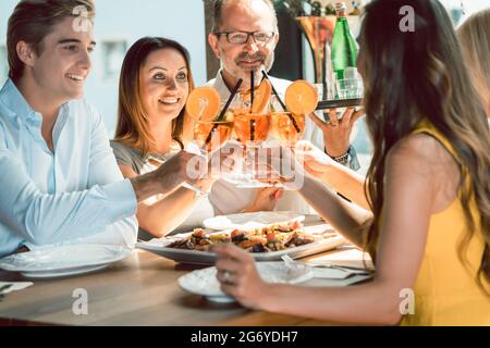 Belle jeune femme en dégustant des cocktails avec son petit ami et ses meilleurs amis servis par un serveur expérimenté dans un restaurant branché Banque D'Images