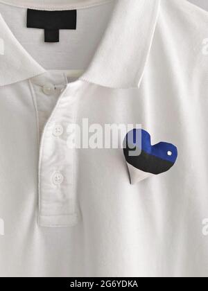 Coeur fait à la main, drapeau estonien, broche sur t-shirt blanc. Célébration de la journée de l'indépendance de l'Estonie Banque D'Images