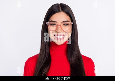 Photo de jeune sourire gai bonne humeur belle fille asiatique en lunettes porter rouge turtleneck isolé sur fond gris couleur Banque D'Images