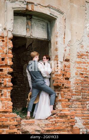 Jeune mariée et couple marié tendre se tenant l'un l'autre. Mariage d'été, femme et homme rouge. Banque D'Images